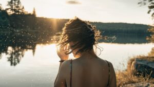 Wet hair care. How to protect your hair before going swimming. Woman swimming in ocean or lake.